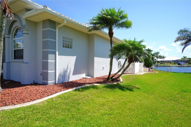 649 Maltese Dr, Punta Gorda, FL 33950 - view of side of home with stucco siding, a yard, and a water view