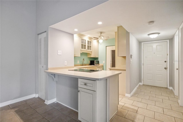 kitchen featuring kitchen peninsula, white cabinetry, ceiling fan, and light tile patterned flooring