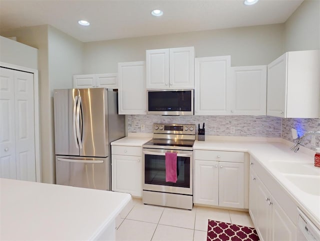 kitchen featuring decorative backsplash, appliances with stainless steel finishes, sink, light tile patterned floors, and white cabinets