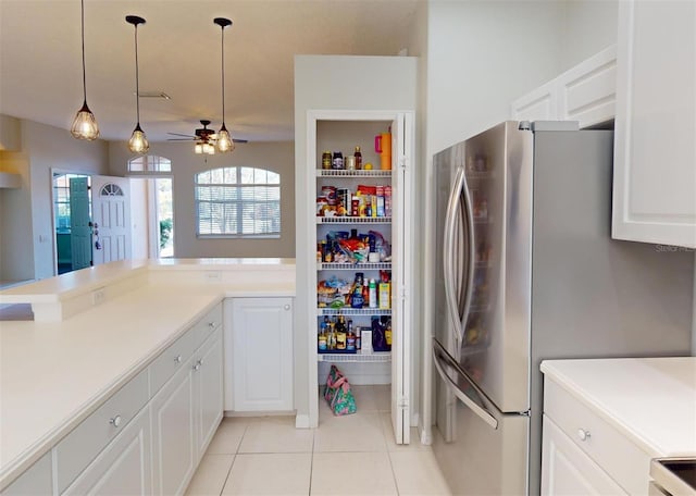 kitchen featuring white cabinets, ceiling fan, light tile patterned floors, decorative light fixtures, and stainless steel refrigerator