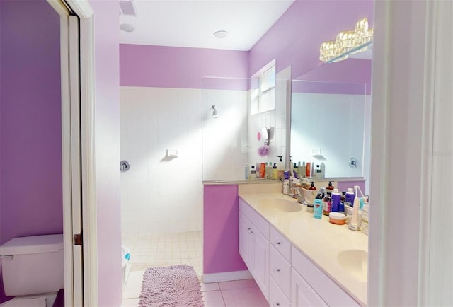 bathroom with a tile shower, tile patterned flooring, vanity, and toilet