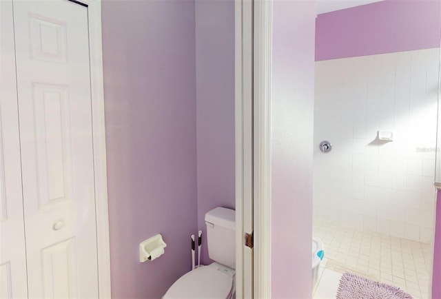 bathroom featuring tile patterned floors, toilet, and tiled shower