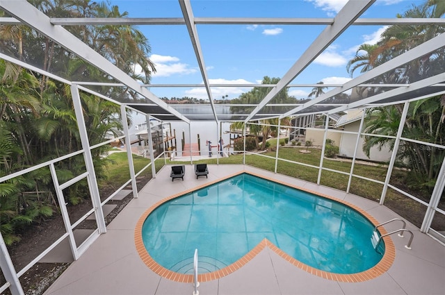 view of swimming pool featuring a lanai, a patio area, and a lawn