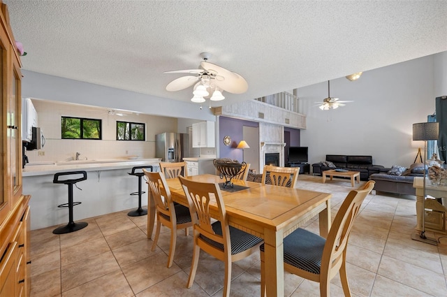 dining space featuring ceiling fan, light tile patterned floors, and a textured ceiling