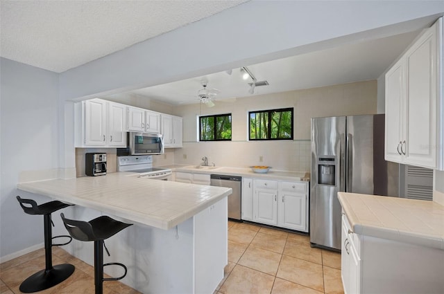 kitchen with kitchen peninsula, white cabinetry, and appliances with stainless steel finishes