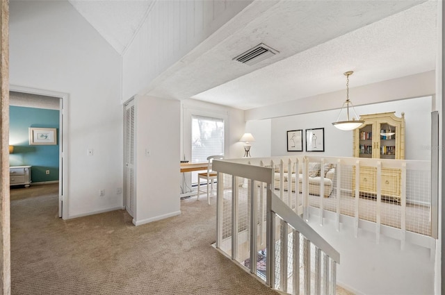 hall featuring carpet flooring, a textured ceiling, and lofted ceiling