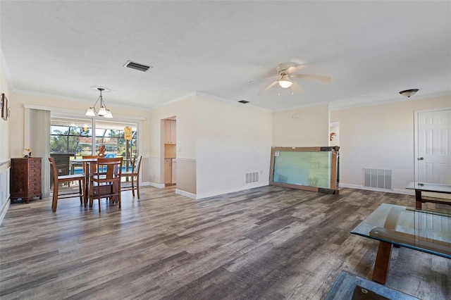 living room featuring dark wood-type flooring, ceiling fan with notable chandelier, and ornamental molding