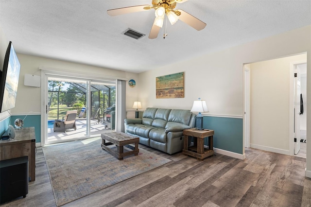 living room with a textured ceiling, dark hardwood / wood-style flooring, and ceiling fan