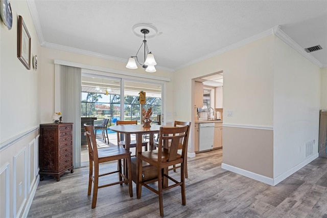 dining space with hardwood / wood-style floors, ornamental molding, and sink