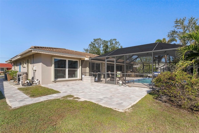 rear view of house with a patio, a lanai, and a lawn