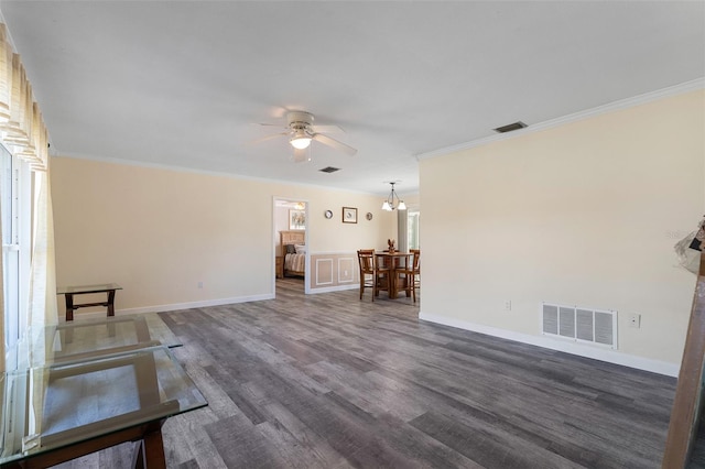 unfurnished living room with ceiling fan with notable chandelier, a healthy amount of sunlight, dark hardwood / wood-style flooring, and crown molding