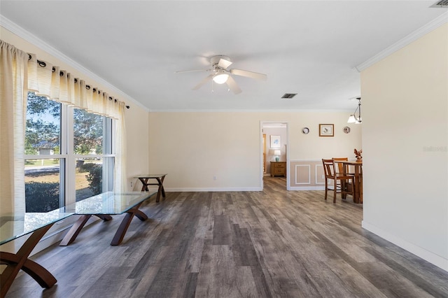 living area featuring ceiling fan with notable chandelier, crown molding, and dark wood-type flooring