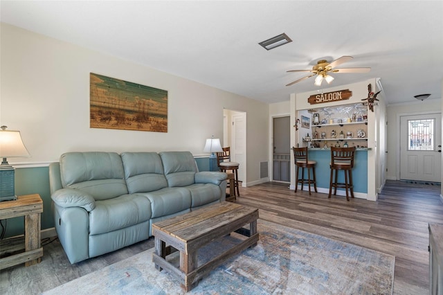 living room with bar area, hardwood / wood-style flooring, and ceiling fan