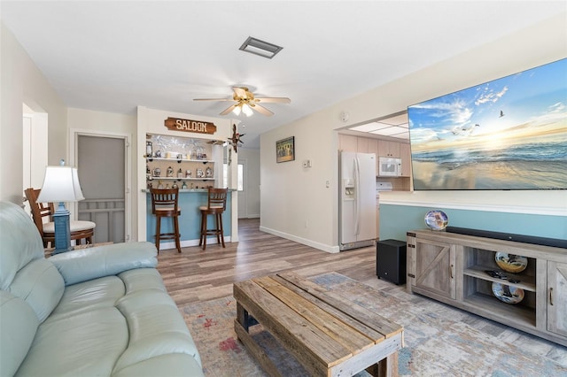 living room with ceiling fan, light hardwood / wood-style flooring, and indoor bar