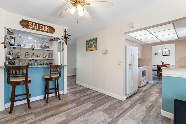 kitchen with white appliances, hardwood / wood-style flooring, ceiling fan, and backsplash