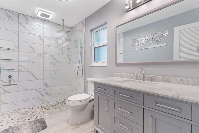 bathroom featuring tiled shower, wood-type flooring, vanity, and toilet