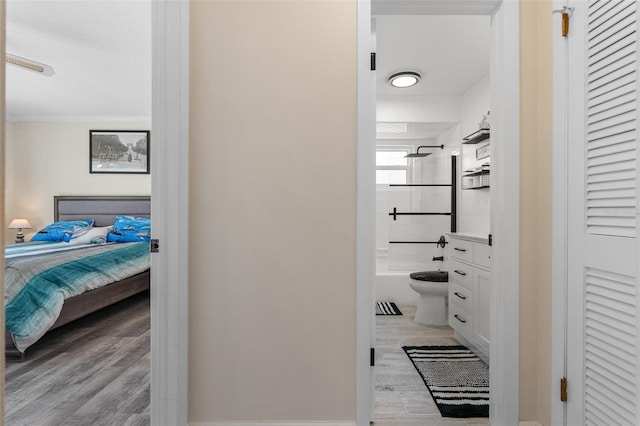 interior space with washtub / shower combination, hardwood / wood-style flooring, toilet, and ornamental molding