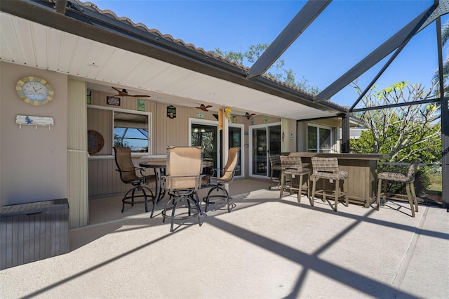 view of patio with ceiling fan, a lanai, and a bar