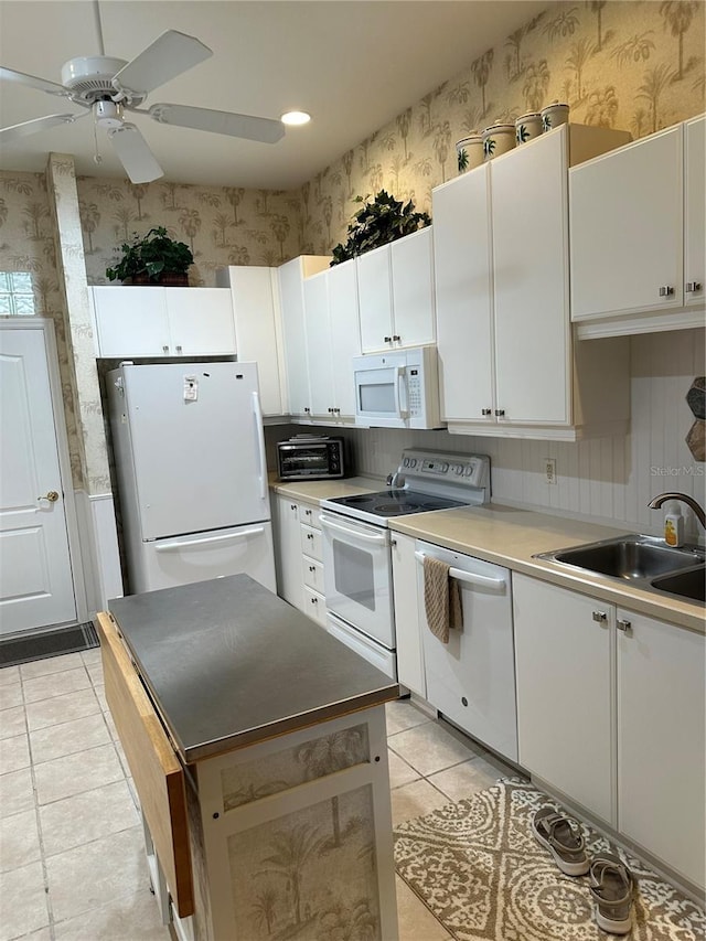 kitchen featuring white appliances, white cabinets, a sink, and wallpapered walls