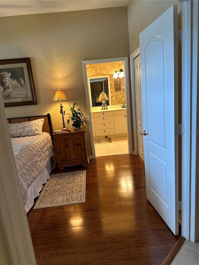 bedroom with ensuite bath and wood finished floors