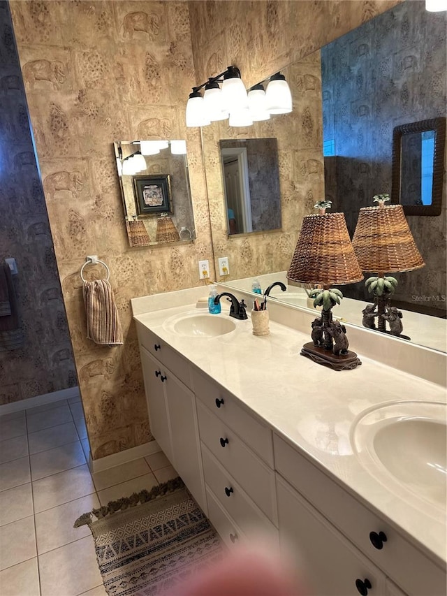 bathroom with double vanity, baseboards, a sink, and tile patterned floors