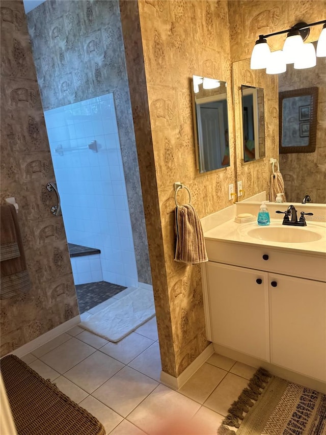 full bathroom with vanity, baseboards, tile patterned floors, walk in shower, and wallpapered walls