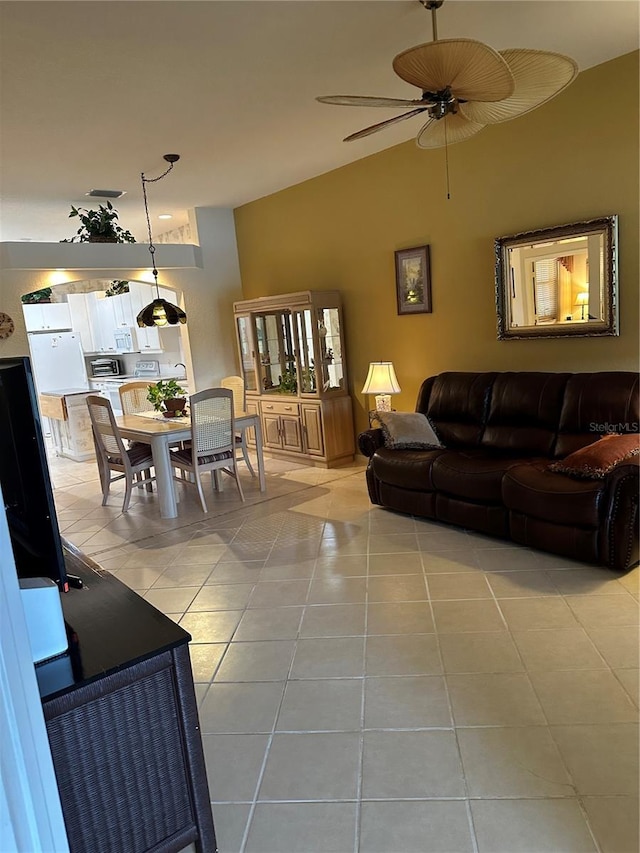 living area with light tile patterned floors, ceiling fan, and vaulted ceiling