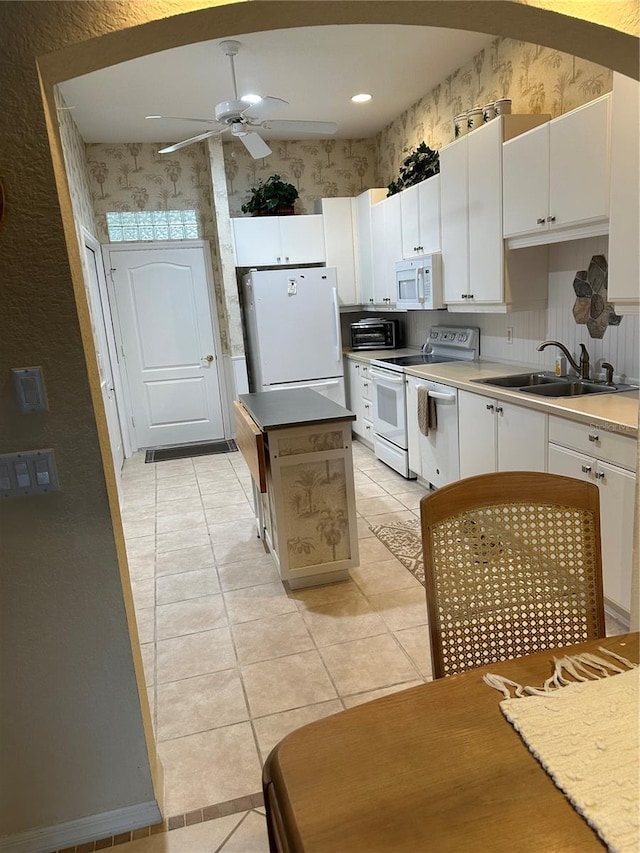 kitchen featuring white appliances, white cabinets, and a sink