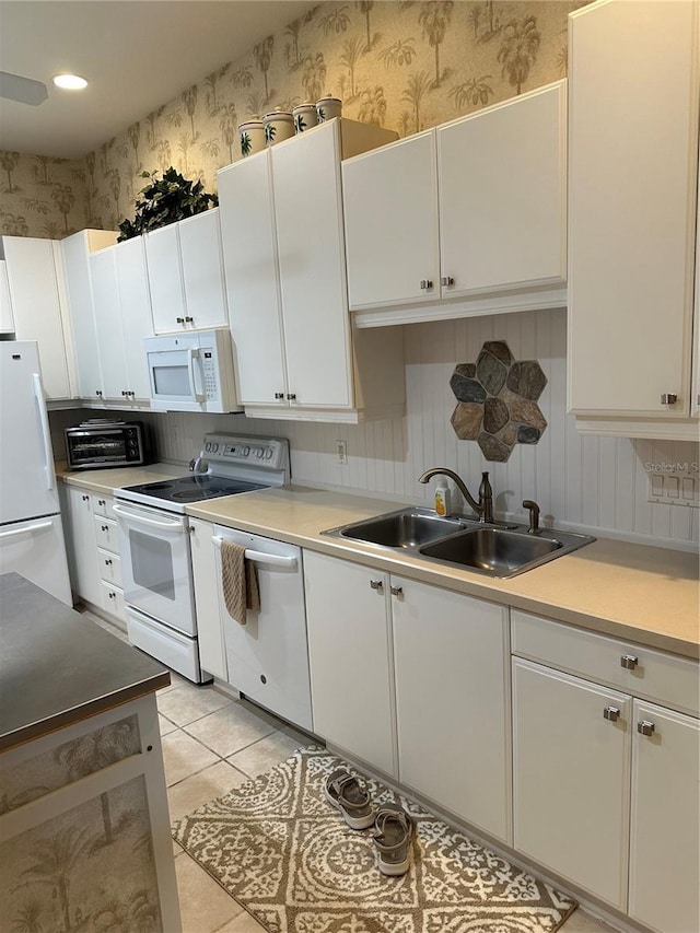 kitchen featuring light countertops, white cabinetry, a sink, white appliances, and wallpapered walls