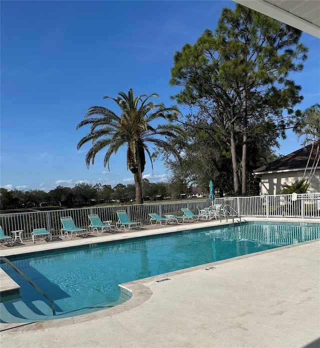 community pool with a patio area and fence