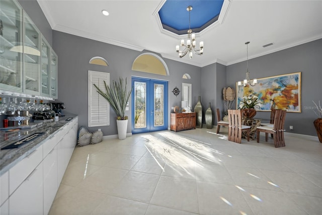 interior space with a notable chandelier, ornamental molding, bar, and french doors