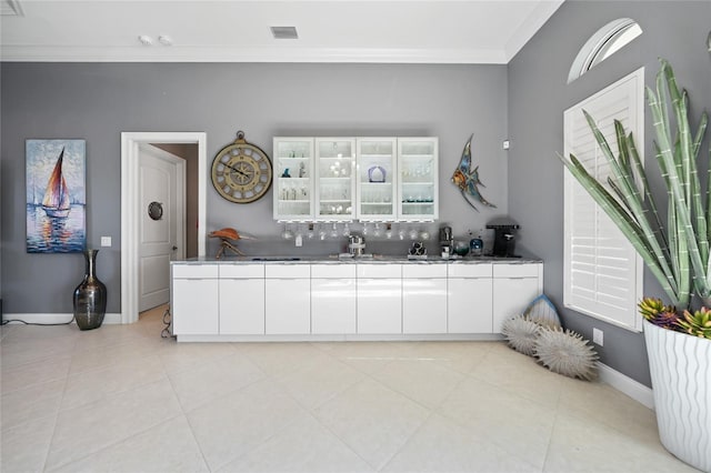 kitchen featuring white cabinets, ornamental molding, and light tile patterned floors