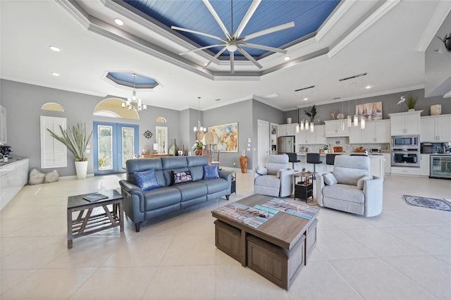 tiled living room featuring french doors, a tray ceiling, an inviting chandelier, and crown molding