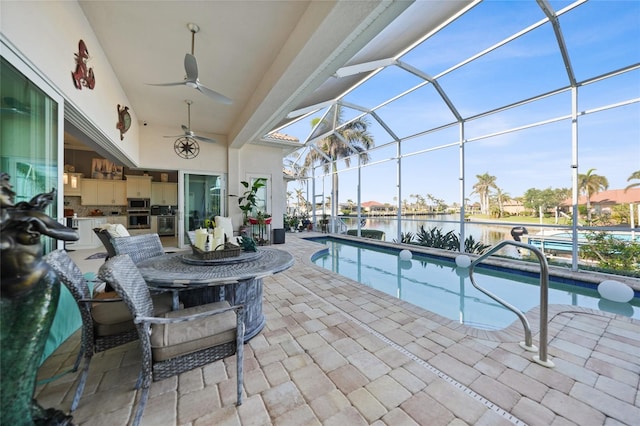 pool with glass enclosure, a patio, a water view, and ceiling fan