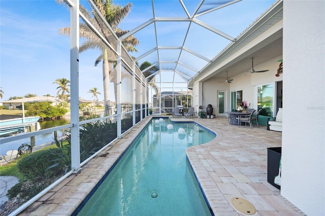 view of pool featuring glass enclosure, ceiling fan, and a patio area