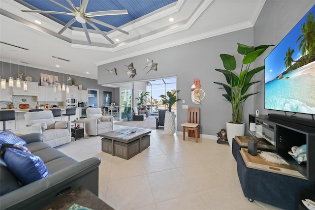 living room featuring crown molding, a raised ceiling, a high ceiling, light tile patterned flooring, and baseboards