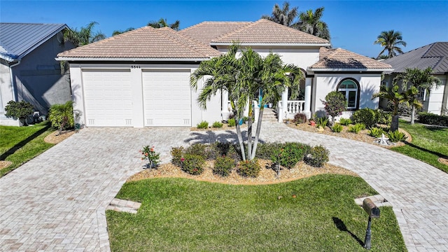 view of front facade with an attached garage, a tiled roof, decorative driveway, and stucco siding