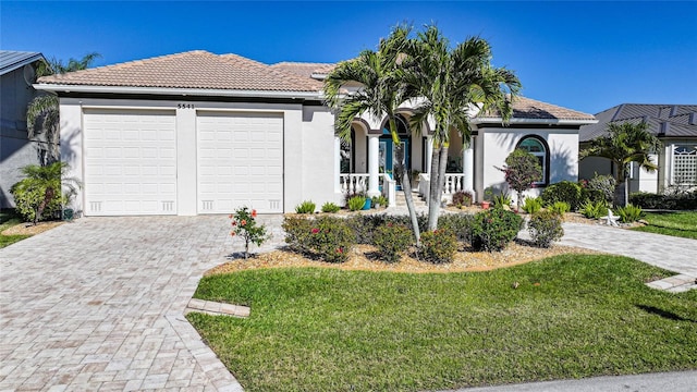 single story home with a garage, a front lawn, decorative driveway, and stucco siding