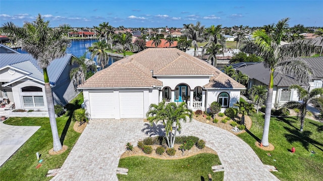 mediterranean / spanish house with a garage, a front lawn, and decorative driveway