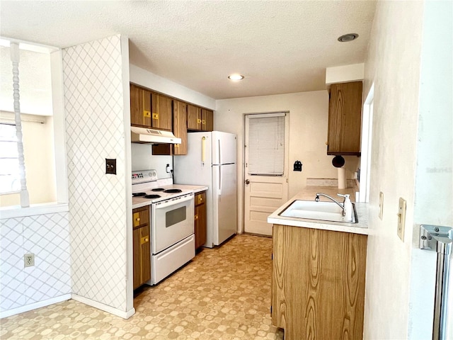 kitchen featuring sink, white appliances, and a textured ceiling