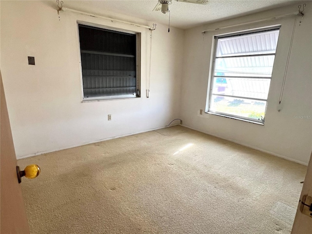 carpeted empty room featuring ceiling fan, plenty of natural light, and a textured ceiling