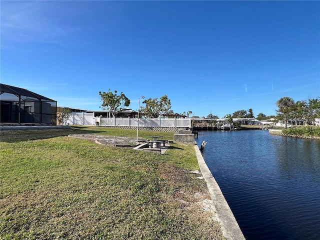 dock area featuring a lanai, a water view, and a yard