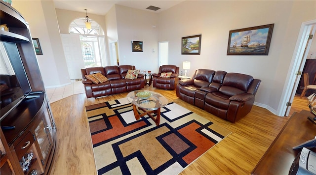 living room featuring a towering ceiling and light hardwood / wood-style flooring