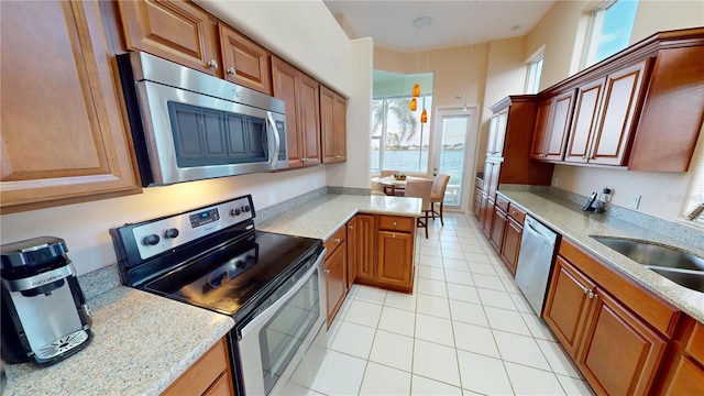 kitchen with light stone countertops, sink, light tile patterned floors, and stainless steel appliances