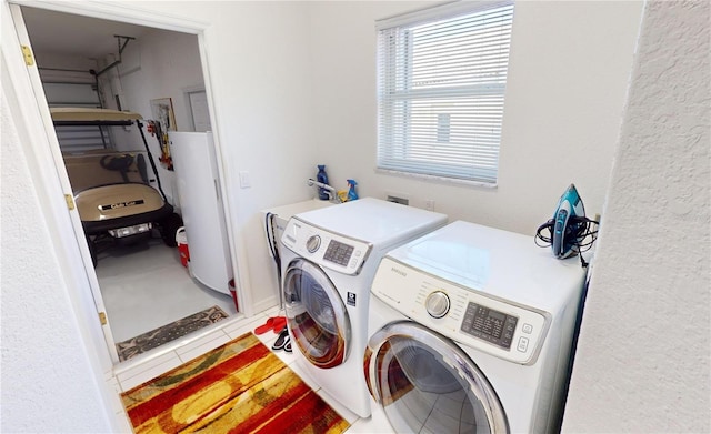 clothes washing area featuring tile patterned flooring, gas water heater, and washing machine and dryer