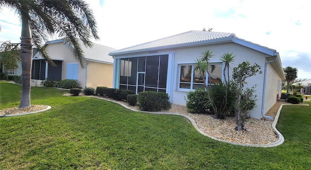 rear view of house featuring a lawn and a sunroom