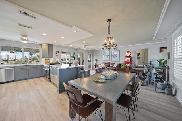 dining space with ceiling fan with notable chandelier, light hardwood / wood-style floors, and crown molding