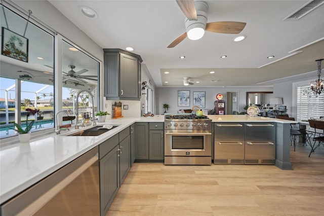 kitchen with kitchen peninsula, gray cabinets, light hardwood / wood-style floors, and appliances with stainless steel finishes