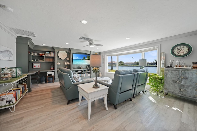 living room with a water view, light hardwood / wood-style flooring, ceiling fan, ornamental molding, and a textured ceiling