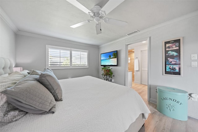 bedroom featuring ceiling fan, light wood-type flooring, ornamental molding, and ensuite bath